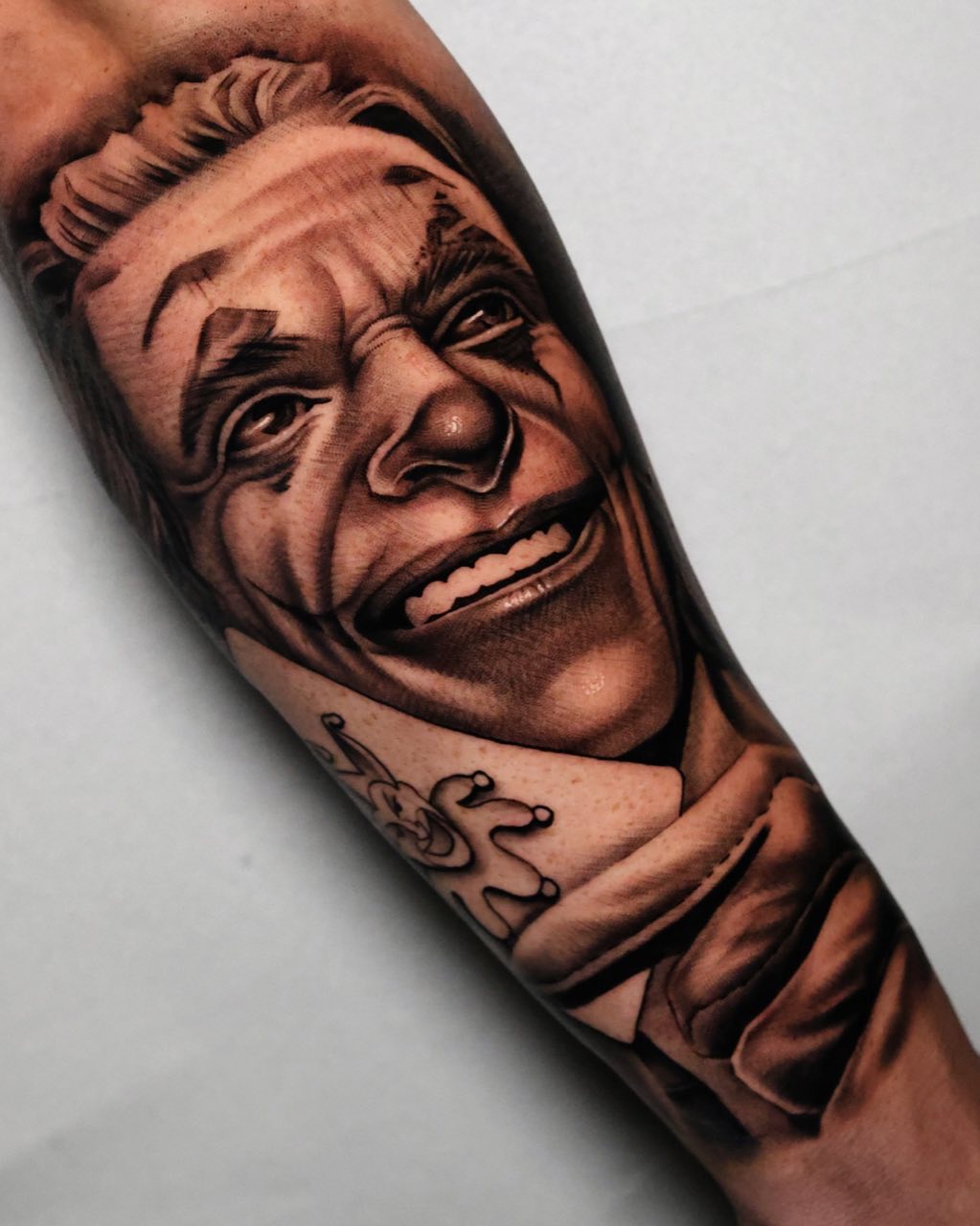 Onderarm met realistisch lachend mannenportret, getatoeëerd door Haissam Mokdad